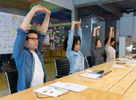 Group of Latin American Workers doing stretching exercises in a business meeting at the office - healthy lifestyle concepts